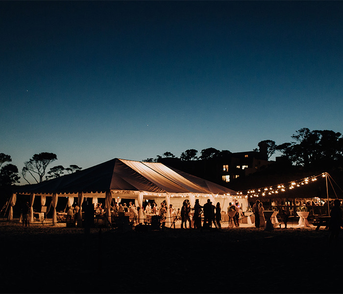 a large white tent with lights and people at dusk
