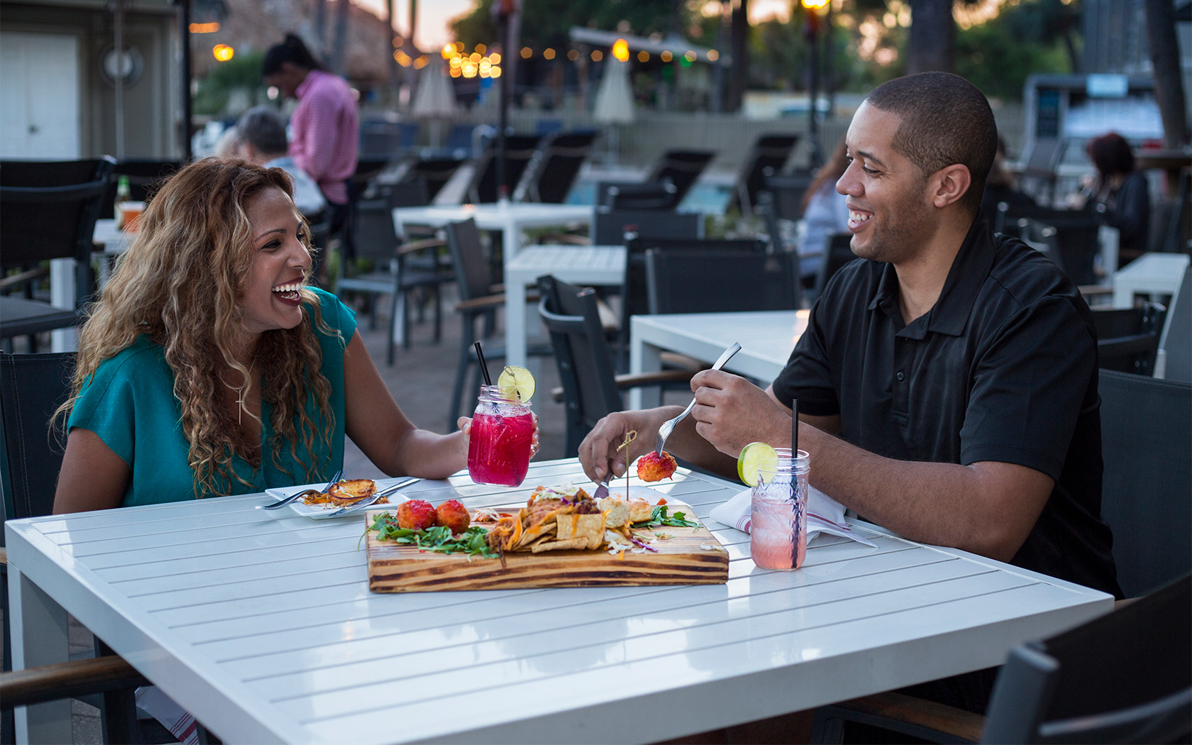 a smiling man and woman sitting at a table outside dining