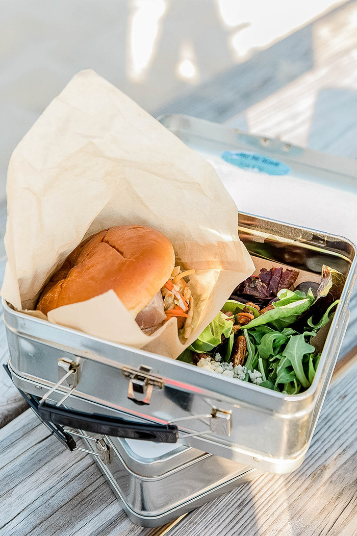 a sandwich and small salad in a tin lunch box