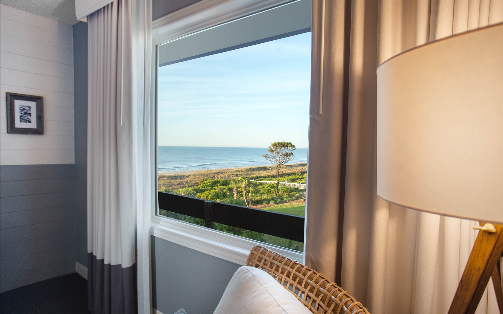 a window from a room with a view of the green grass and the ocean 