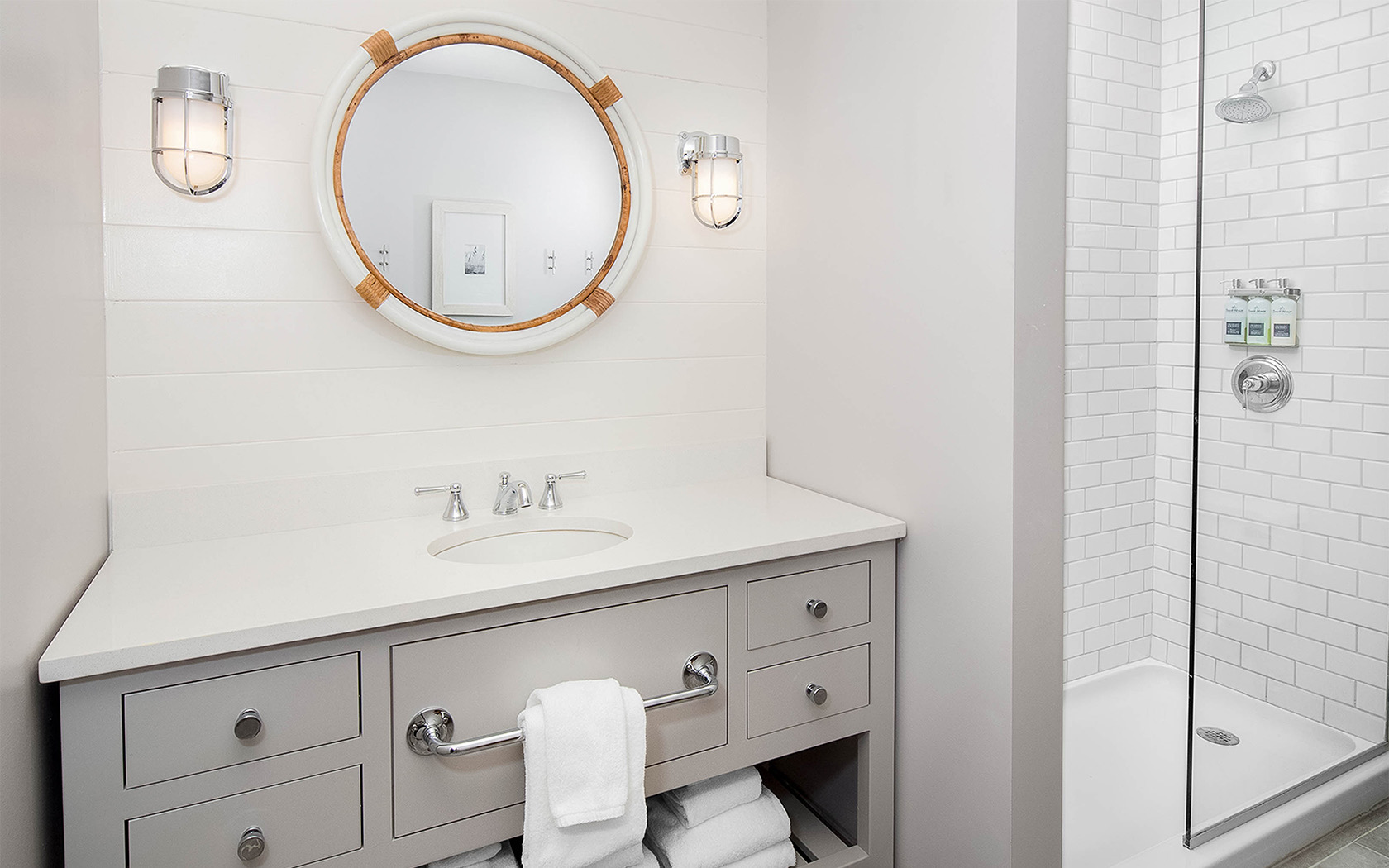 a bathroom vanity with a round mirror hanging on the wall above
