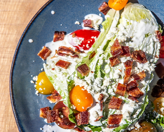 a salad with dressing, bacon, and tomatoes