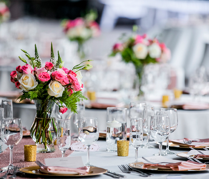 a table set up for an event with pink and white flowers in the middle of the table