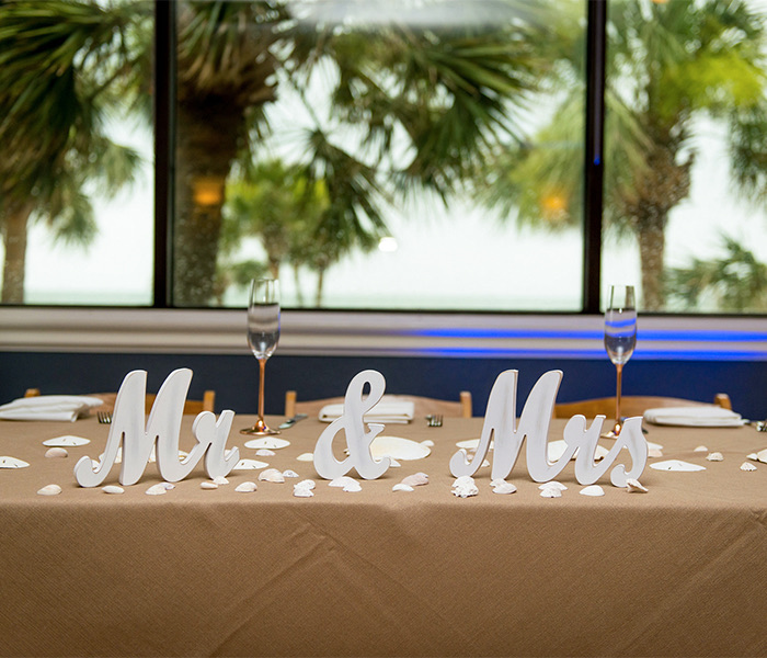 a table set up for mr. and mrs. in front of a window with palm trees in the distance