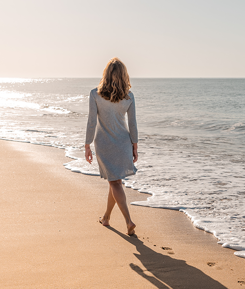 a woman walking along the ocean during the day