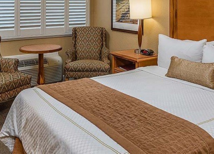 Queen size bed with a nightstand and lamp net to seating area with two chairs and a table