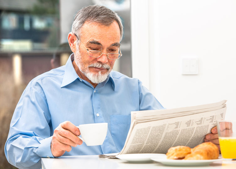 Gentleman reading the newspaper holding coffee cup