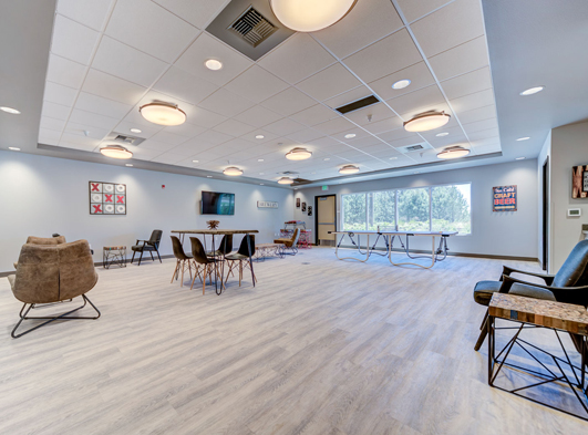 Rouge social room with tables, chairs a flatscreen television and a ping pong table