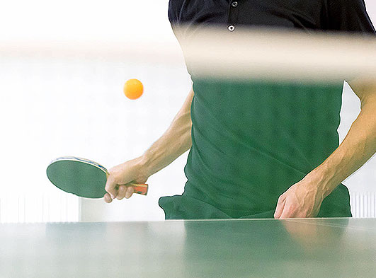Man holding ping pong paddle with ping pong ball