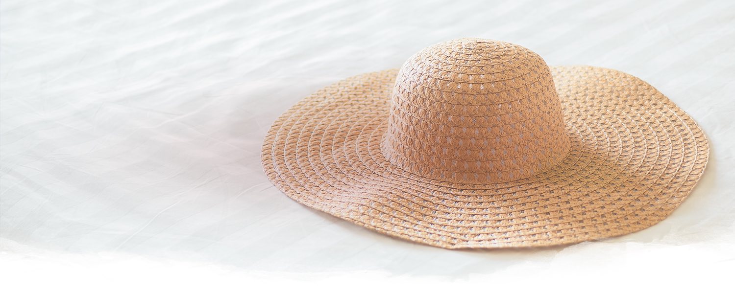 floppy hat sitting on a white linen bed