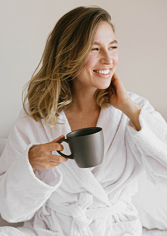 Closeup of a happy woman drinking coffee at bed