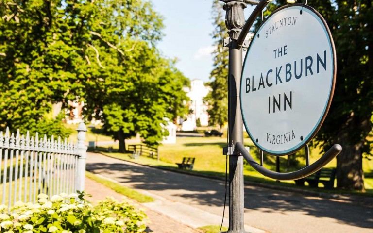 View of The Blackburn Inn sign and some green plants 