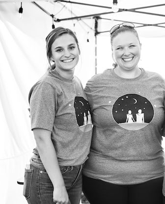 woman standing together under a tent