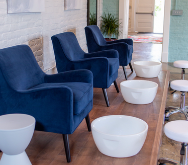 Three dark blue velvet chairs next to each other with white bowls in front of them