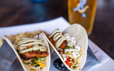 close up on the fish tacos with green crema sauce and other vegetable toppings