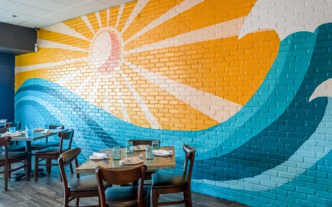 art mural behind the tables of the sun and a big wave