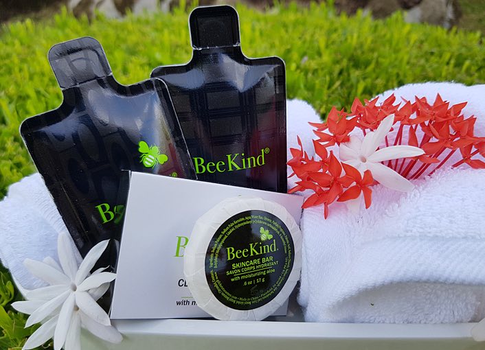 sampls of beekind skincare in a basket with a white towel decorated with white and pink flowers