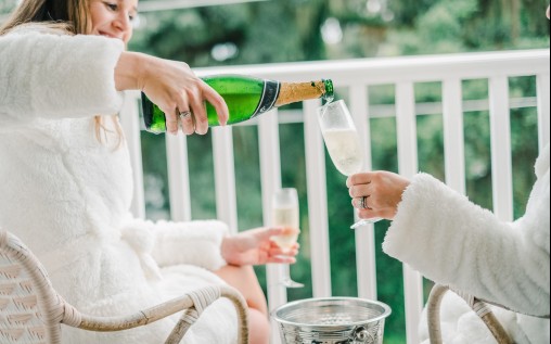 2 married women sitting and drinking champagne outdoors