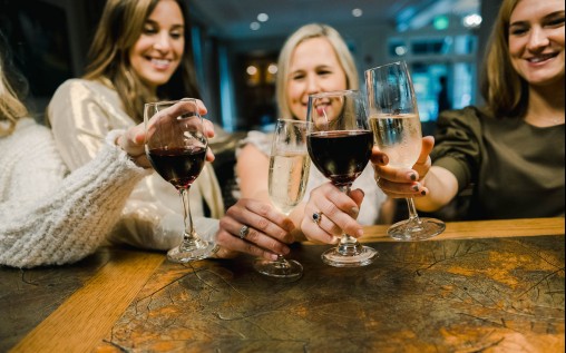 4 women in a bar drinking a glass of white and red wine