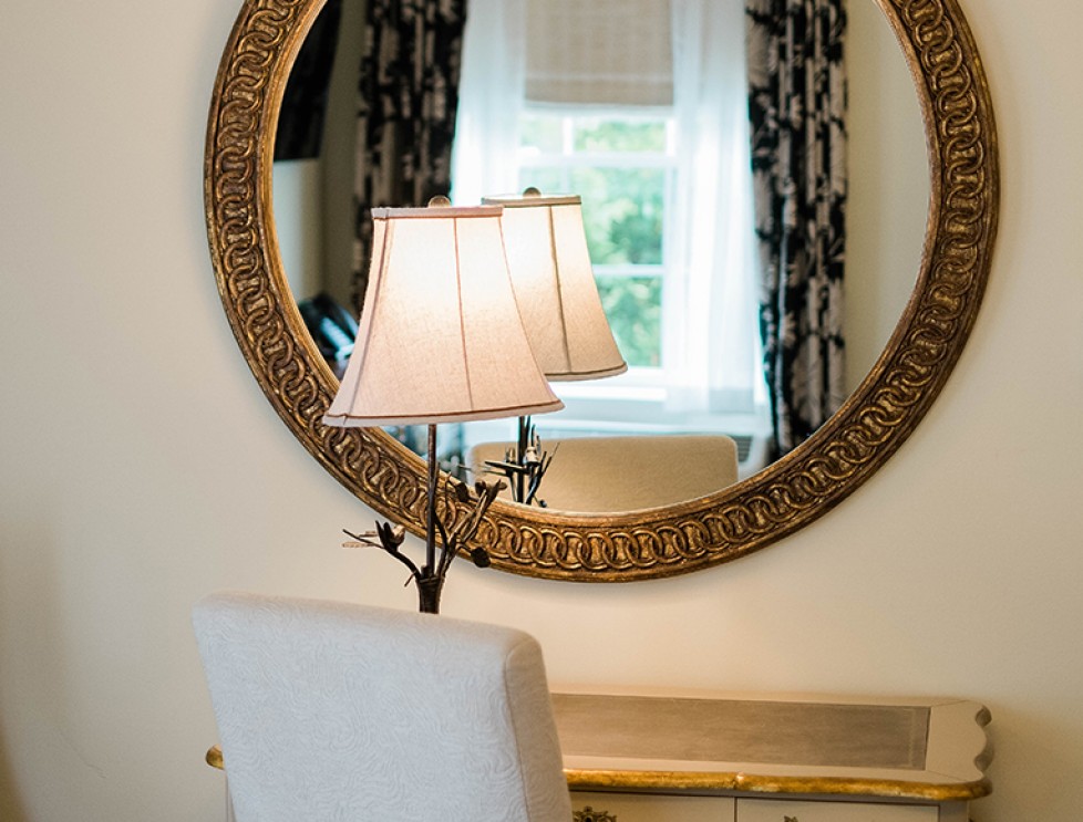view of a desk with a table lamp and a mirror