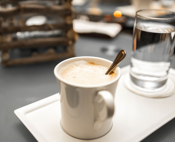 Close up of mug with coffee & glass of water on tray
