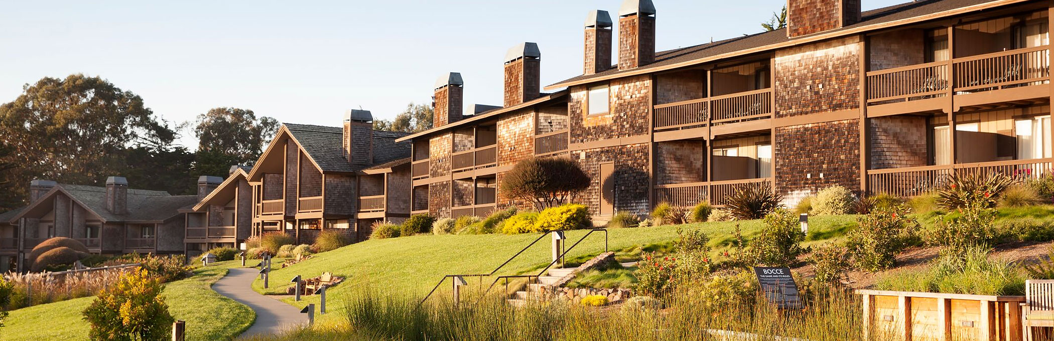 Brick building property with chimneys surrounded by greenery & tall grass