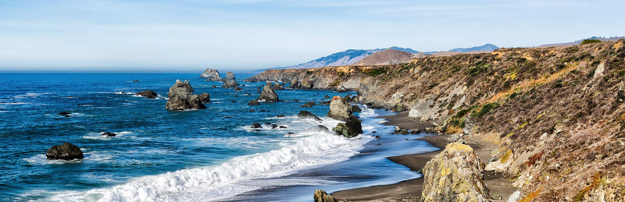 Waves crashing against shore with jetty rocks