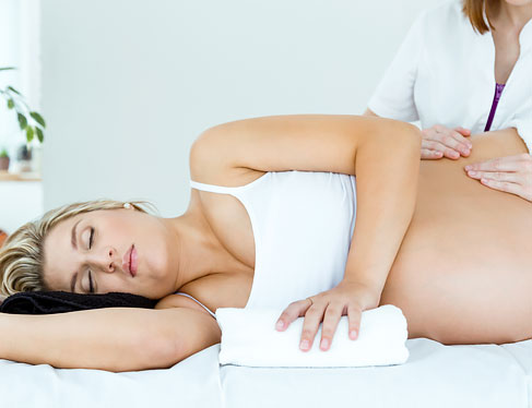 Pregnant woman laying down in spa getting massage