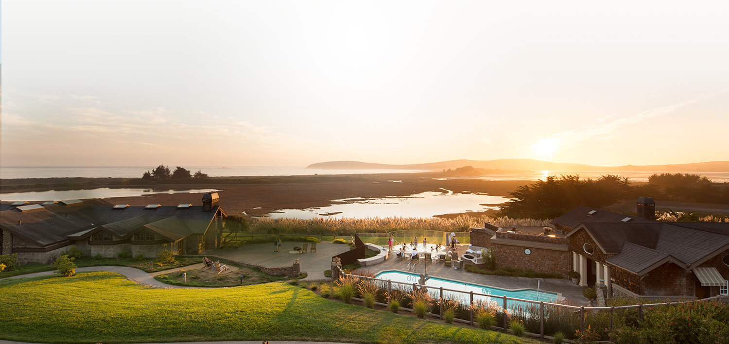 Property with swimming pool next to lake while the sun sets