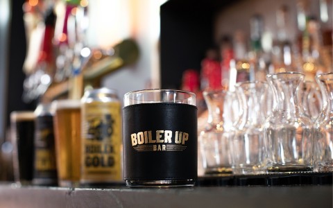 boiler up bar labeled cup with other drinks and glassware behind it