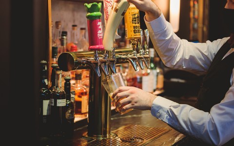 Bartender pouring a glass of beer from a tap