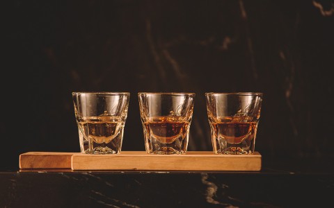 Three shot glasses filled with bourbon