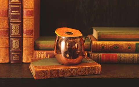 Copper mug with orange peel on top, placed on a book