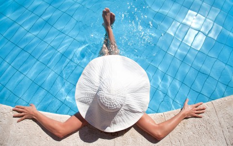 a woman in a white hat enjoying the pool