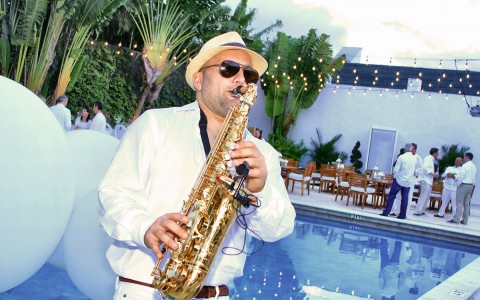 a man playing a saxophone by the pool 