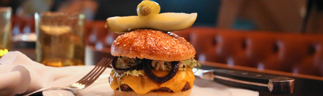cheeseburger with pickle on top of the bun