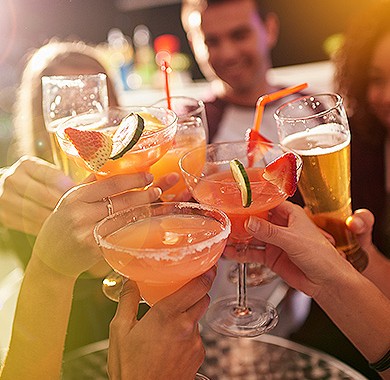 Group of people toasting with fruit cocktails and beer