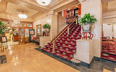 Interior view of the front entrance & lobby stairs with red carpet & gold railing down the middle at our downtown louisville hotel 