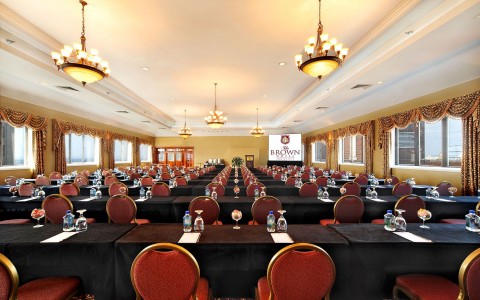 Interior view of the Brown Meeting room, empty chairs, portrait style photo & arching glass windows at our hotel in Louisville, KY  