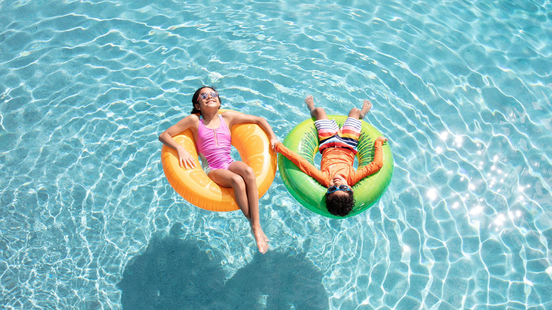 Two children lounging on pool floats 
