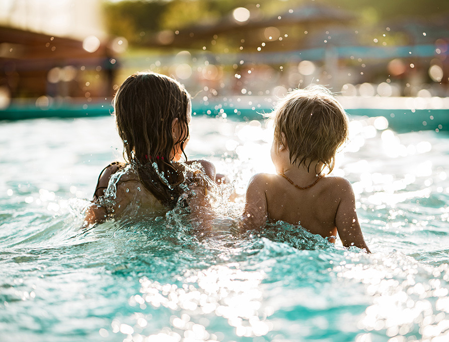 Two little kids splashing around in the pool