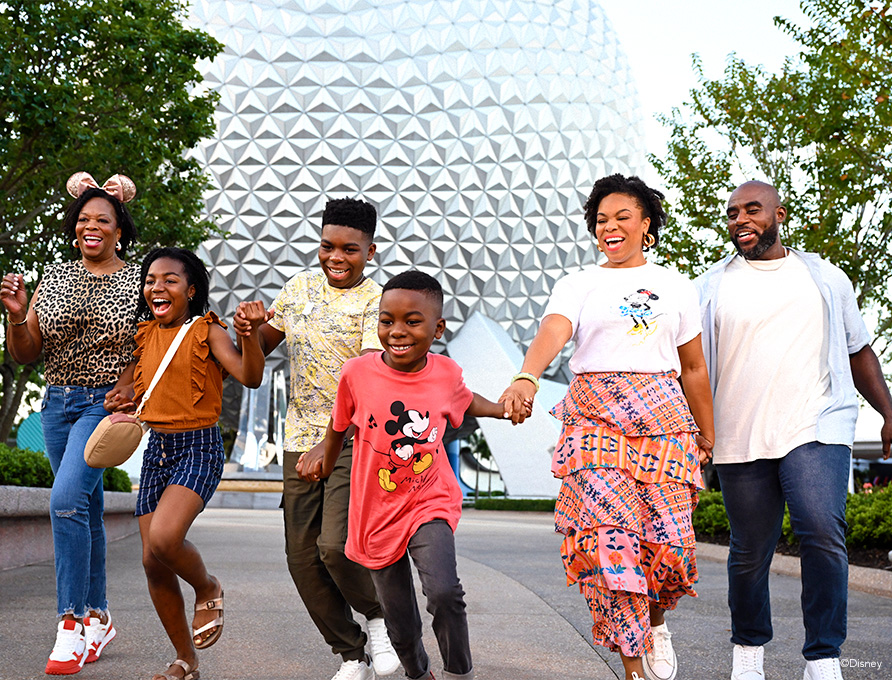 multigenerational family walking hand in hand in front of the epcot ball