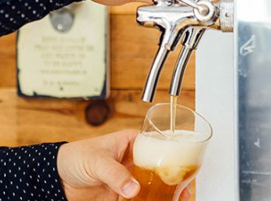 person pouring beer out of a tap