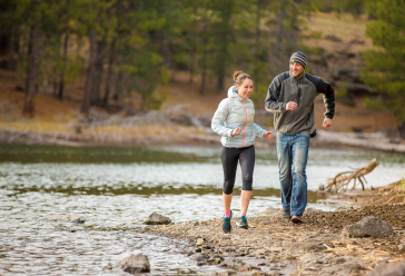 Couple running alongside a lake