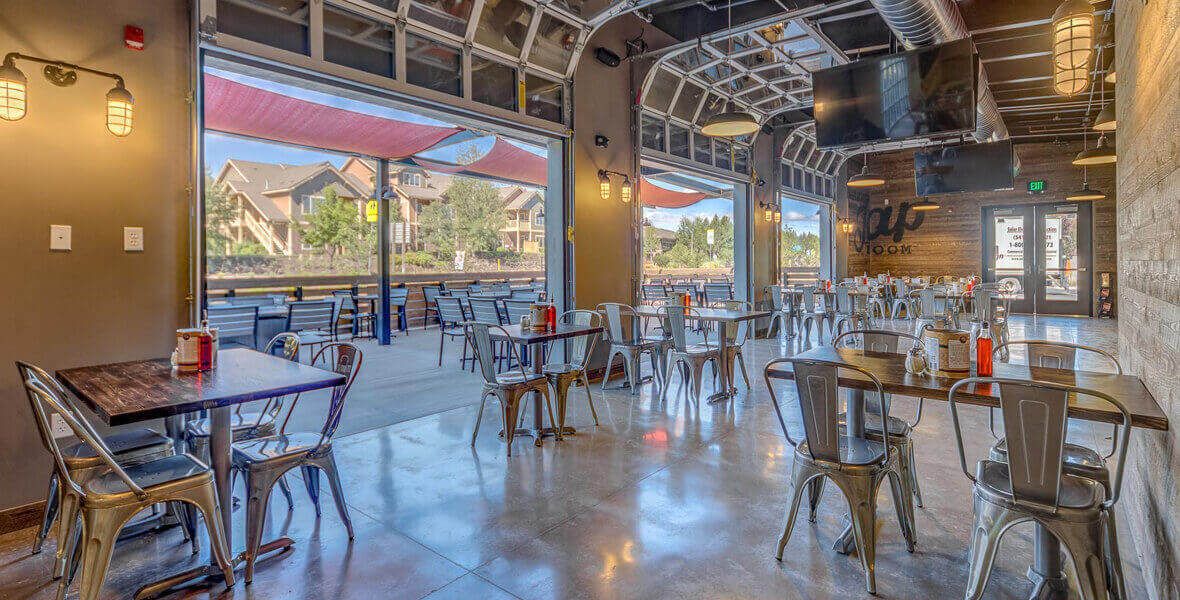 Zpizza and Tap room dining area with many wood tables, metal chairs and an outdoor seating area