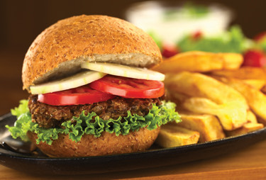 A grilled burger topped with lettuce, tomato, and onion served with thick cut fries.