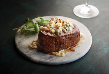 A filet topped with bleu cheese crumbles and demi glaze.
