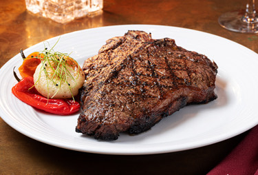 A T-bone steak served with grilled onion and pepper.