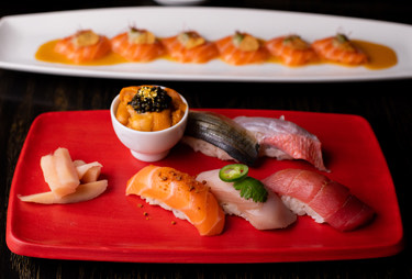 Two plates of sushi and sashimi served with roe.