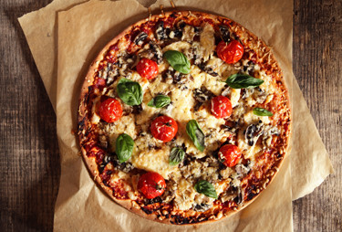 An aerial view of a tomato and mozzarella pizza topped with fresh basil.